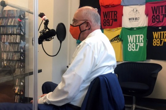 RIT President Munson wearing a mask and speaking into a microphone in a radio station.