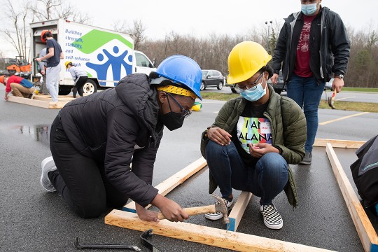 two students building a wall frame for a house.