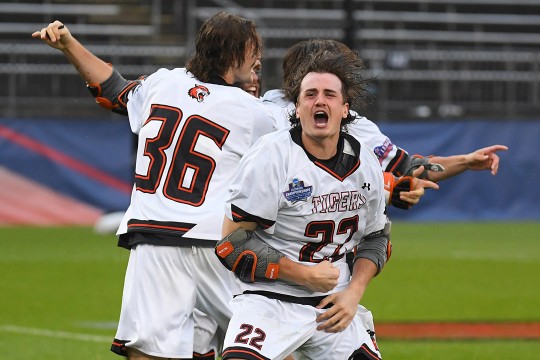 three men's lacrosse players celebrate a goal.