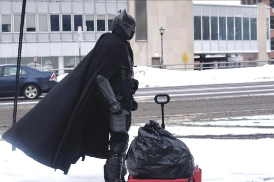 a person dressed as Batman standing on a city street.