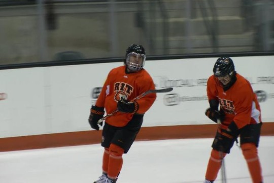 two RIT men's hockey players skating on the ice.