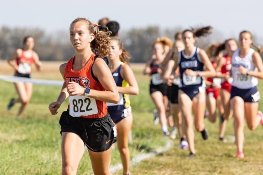 group of track and field student athletes running outdoors.