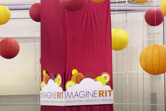 paper lanterns and a banner with the Imagine RIT logo hanging from a ceiling.