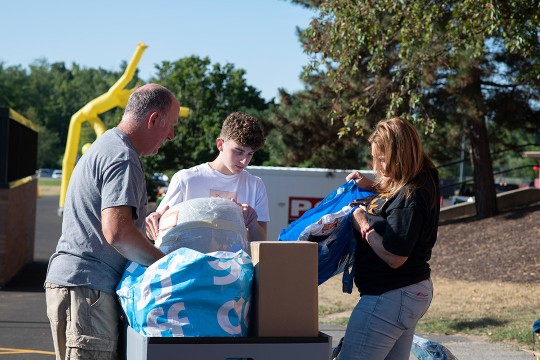 student and parents loading dorm supplies onto a cart.