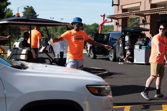 student volunteering motioning for a car to pull forward.