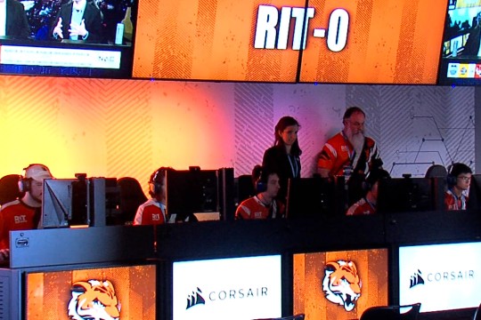 five college students sitting in a row on computers in an E sports tournament.