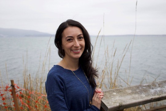 environmental portrait of a woman standing beside a body of water.