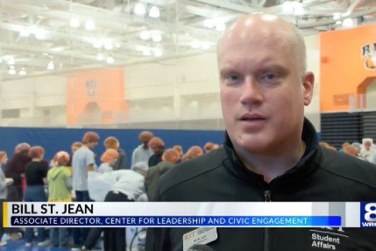 a chyron appears with the name Bill St John as he appears behind it.