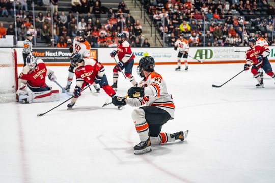players on the R I T mens hockey team skate on the ice near the goal.