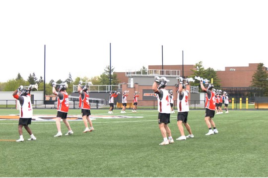 players on the R I T mens lacrosse team practice on the field in playing gear
