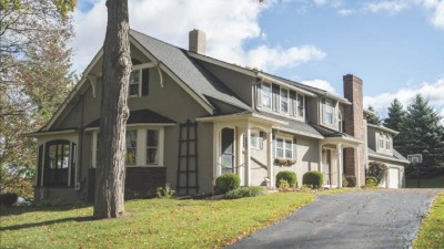 exterior of a two-story house with two brick chimneys and two covered entrances.