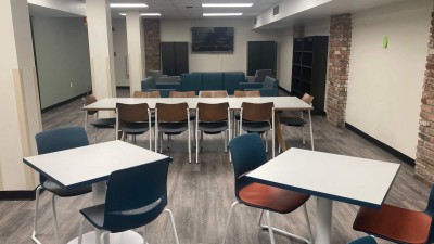 a lounge space with a long table with chairs and two smaller tables with chairs.