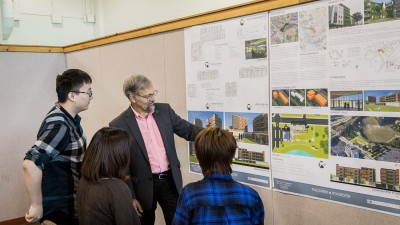 Architecture teacher talks to students about designs.