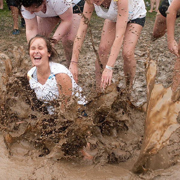 An RIT student falling into the mud during Mud Tug