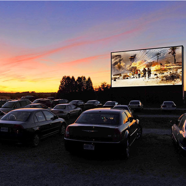 Cars at a drive-in theatre watching a movie at night