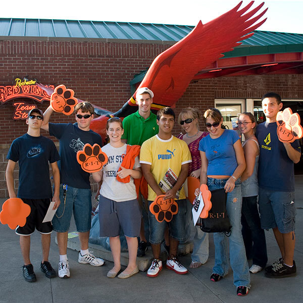 A group of RIT students in front of the Red Wings statue at Frontier Field