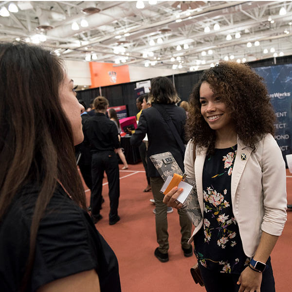 An RIT student talking to an employer at a career fair