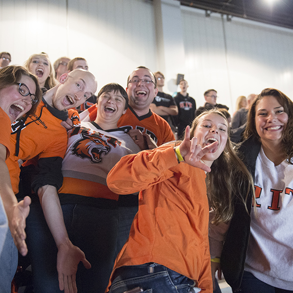 Students standing and cheering at RIT hockey game.