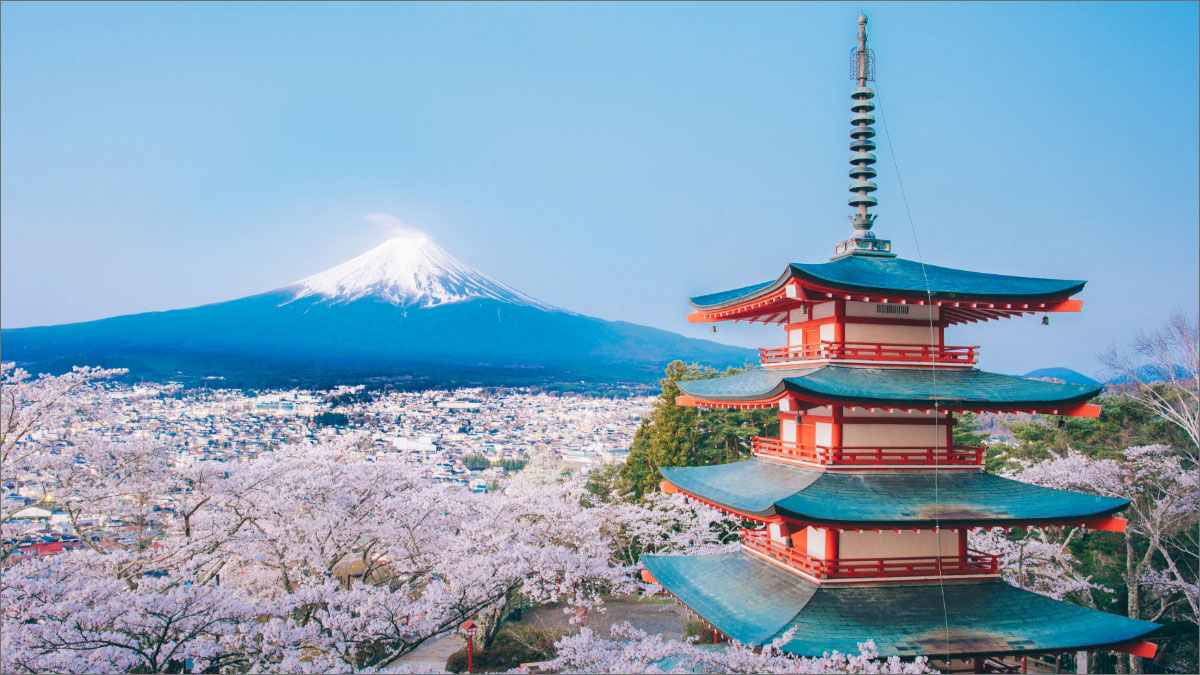 Chureito Pagoda with Mount Fuji in the background, surrounded by cherry blossoms under a clear blue sky.