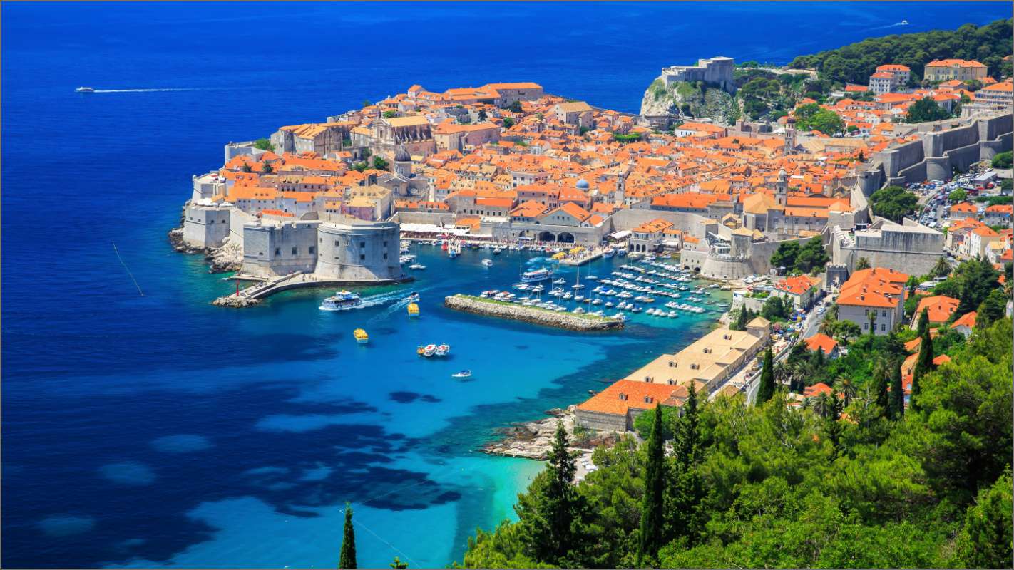 A stunning aerial view of Dubrovnik, Croatia, showcasing its historic walled city, orange rooftops, and turquoise Adriatic Sea.
