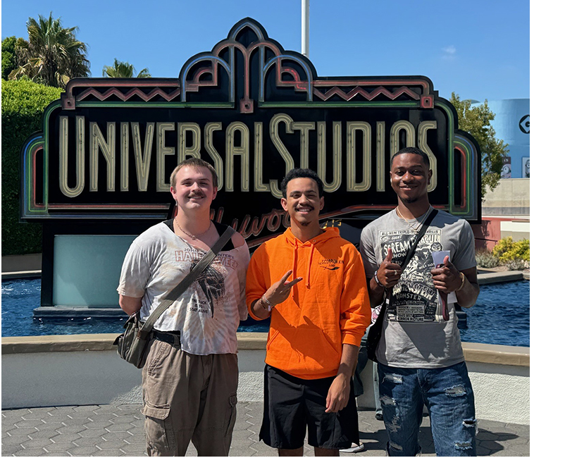 Three students in front of Universal Studios sign