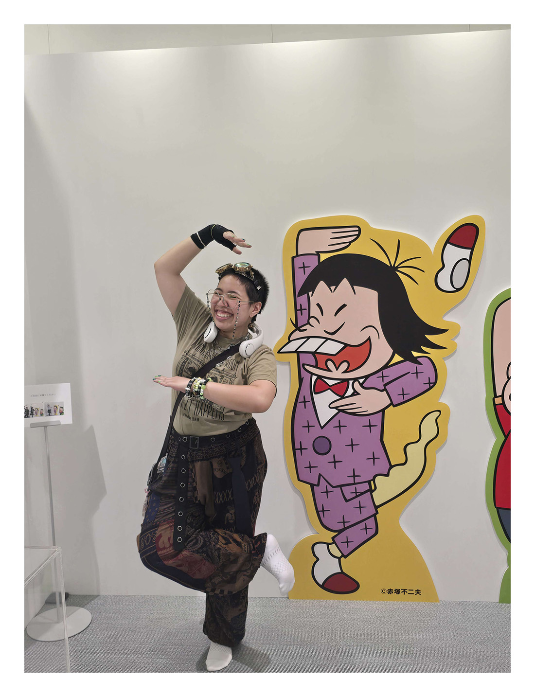 Wonder Mia posing in front of a colorful manga art cutout in Japan