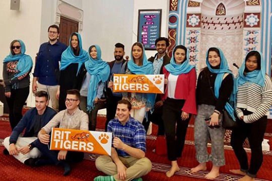 Students holding "RIT TIGERS" banners posing for a photo in Dubai.