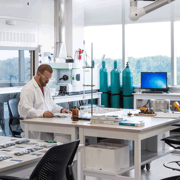 man in white lab coat working at a table in a lab