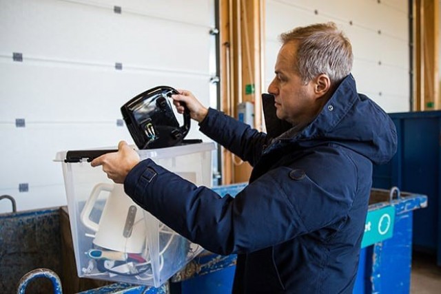 man putting old electronics into recycling bins.