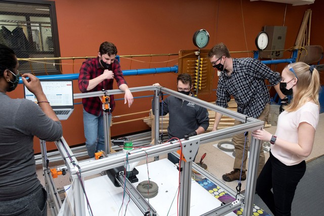 five students observing a 3D concrete printer.