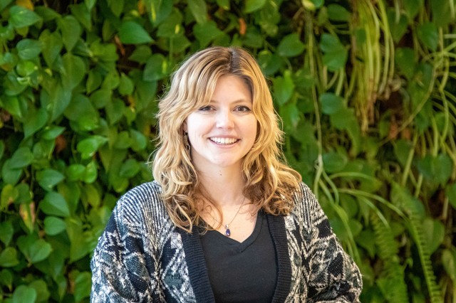 woman standing in front of a plant wall.