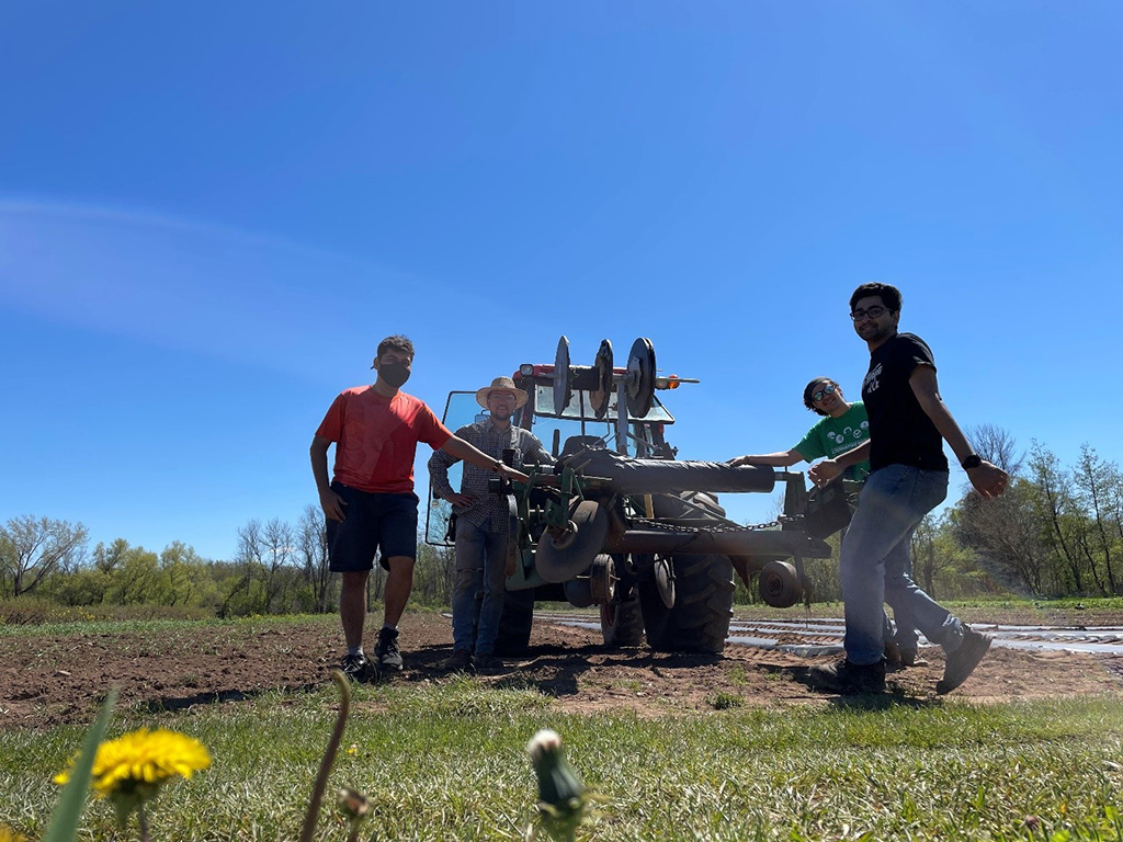 Researchers in a field with equipment to lay down film.