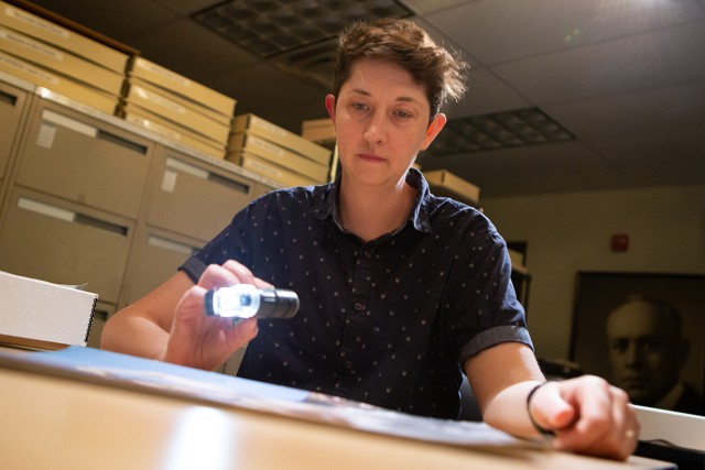 An I P I employee shines a light on a specimen to examine it.