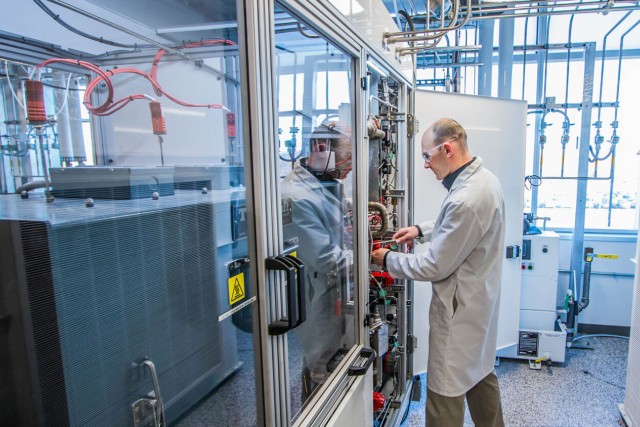Man in lab coat working on a panel in a fuel cell lab.