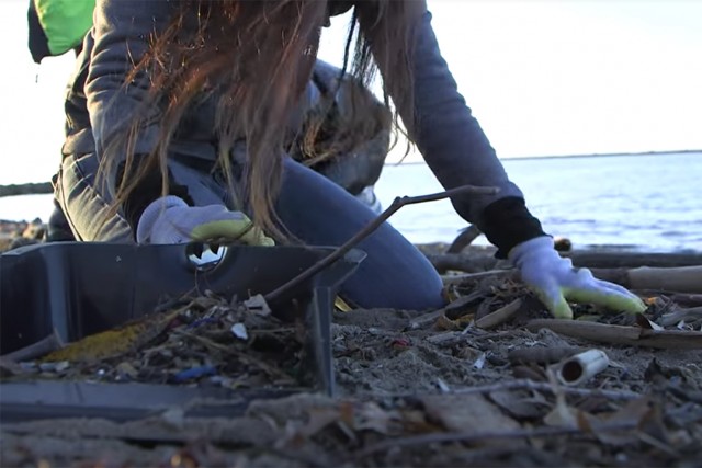 Person picks up garbage beside the lake.