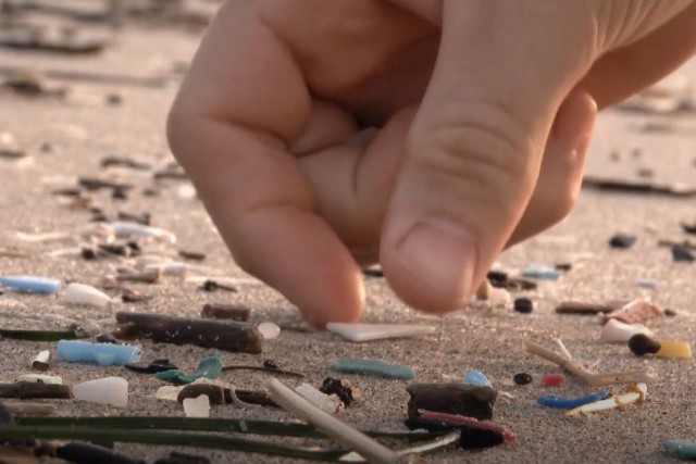 Close-up of hand picking up small pieces of plastic.