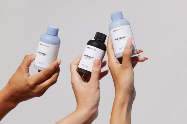 Hands holding hair-care products.