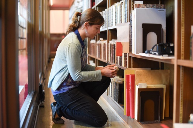 researcher examining row of books in a library.