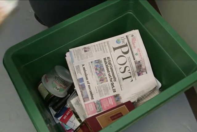 recycling bin with newspapers and plastic containers.