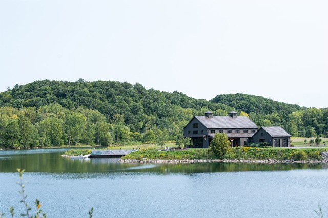 lodge on a lake with treed hills in the background.