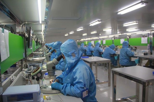 People in blue sanitary suits working in a lab.