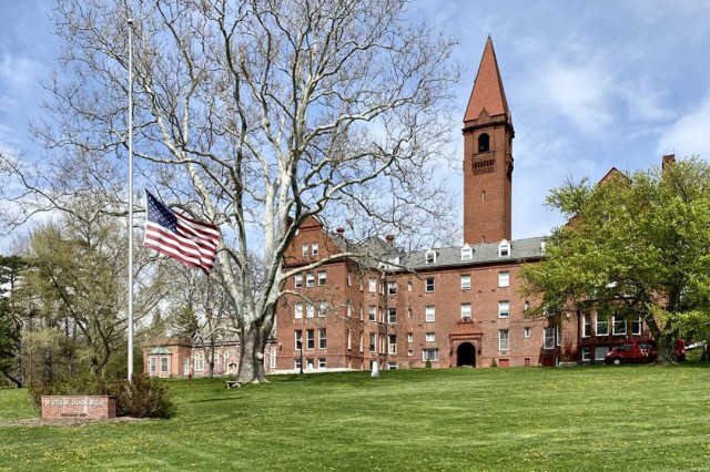exterior of a brick building with a tall tower and an American flag at Wells College.