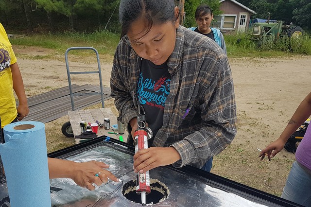 Person works on a solar panel furnace outdoors.