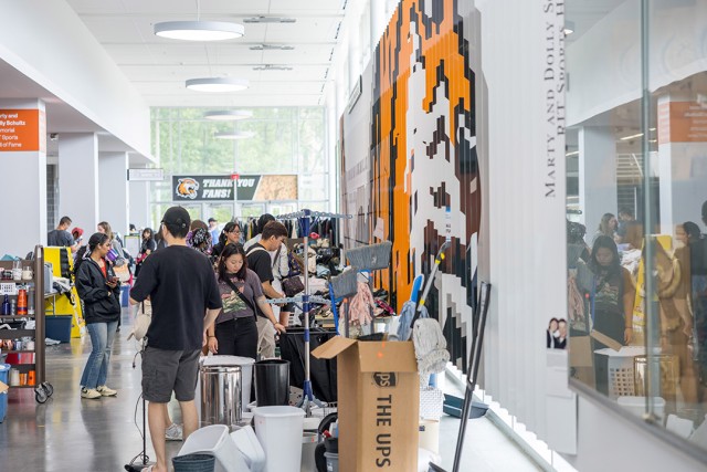 students walk around a light filled hallway surrounded by donated items for purchase.