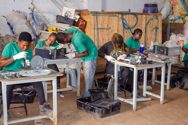 People work at a small tables at an electronic recycling facility.