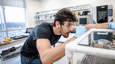 Man in goggles working on a plastic tube model design.