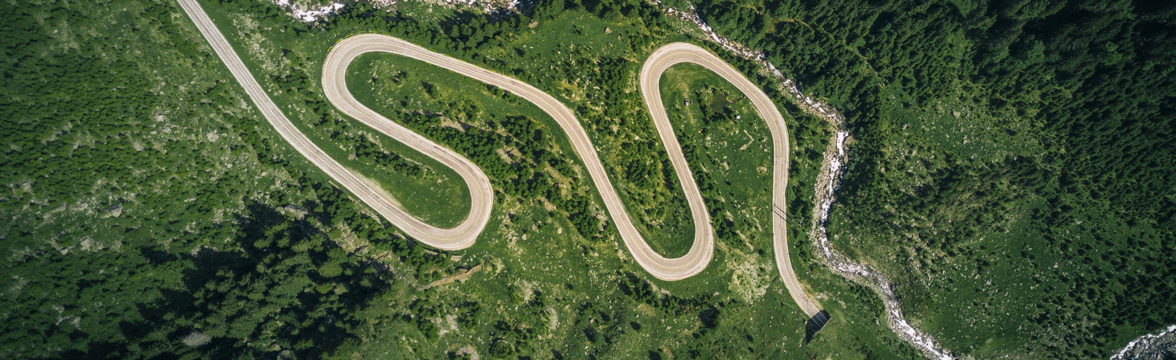 aerial view of a long, winding road in a green valley