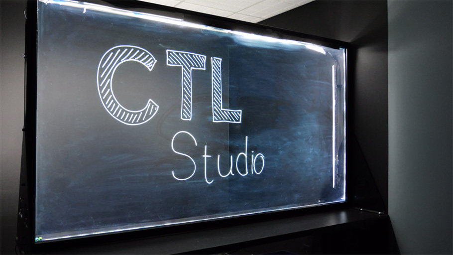 a lightboard set against a dark studio background with the words C T L Studio written on the glass.