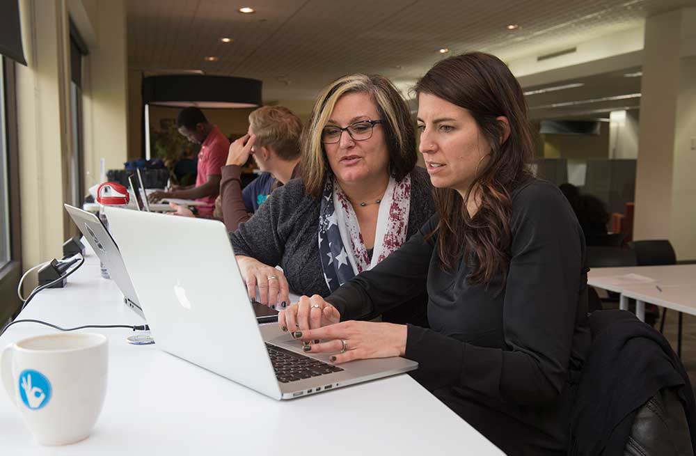 Two women working on a laptop in a coffee shop