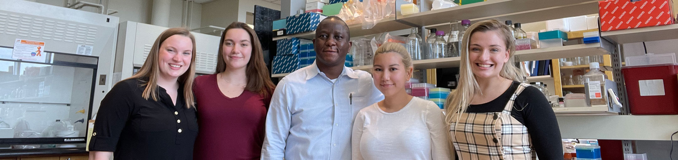 Dr. Bolaji Thomas posing for a photo with four of his lab members.